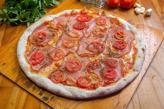 Frisch belegte Pizza mit Tomaten und Käse auf einem Holzbrett angerichtet